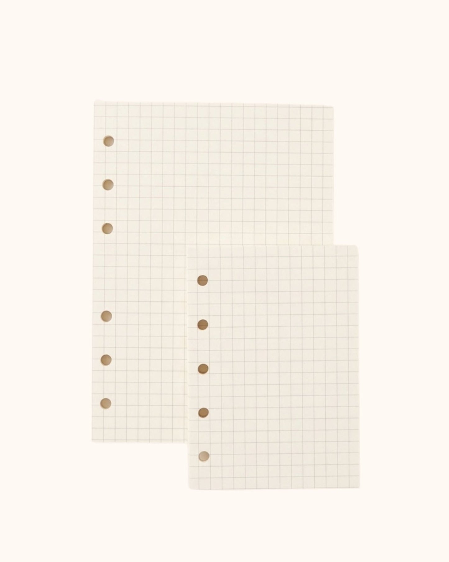 Overhead view of two Kuura premium grid graph paper refill sheets in A6 and A7 sizes with standard 5-hole and 6-hole punching. High-quality, ghosting-resistant paper perfect for neat handwriting, planning, and precise diagrams.