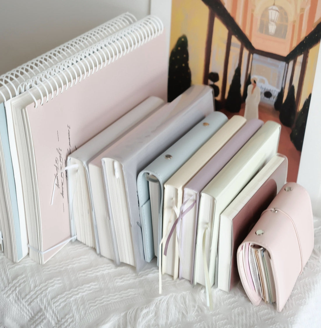 A collection of pastel notebooks and journals in pink, blue, and cream