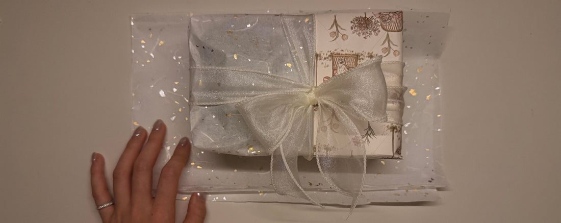 A beautifully wrapped aesthetic stationery gift featuring vintage floral paper, gold-flecked tissue, and a sheer ribbon bow.