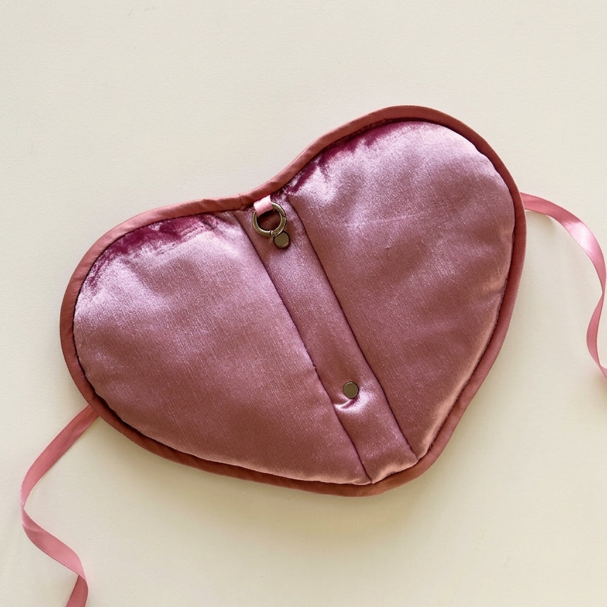 Heart-shaped pink journal cover with a strap on a light beige background