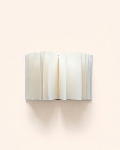 Close-up overhead photograph of Kuura's A5 and A6 Unlined Hardcover Notebook opened flat, showing fanned-out, thick, premium creamy blank pages. A minimalist, bleed-resistant journal base for fountain pen friendly writing, sketching, and memory keeping.