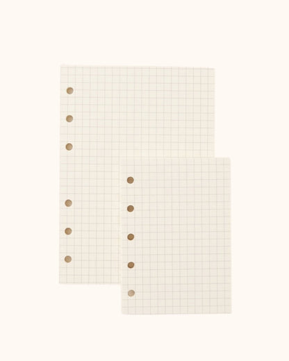 Overhead view of two Kuura premium grid graph paper refill sheets in A6 and A7 sizes with standard 5-hole and 6-hole punching. High-quality, ghosting-resistant paper perfect for neat handwriting, planning, and precise diagrams.