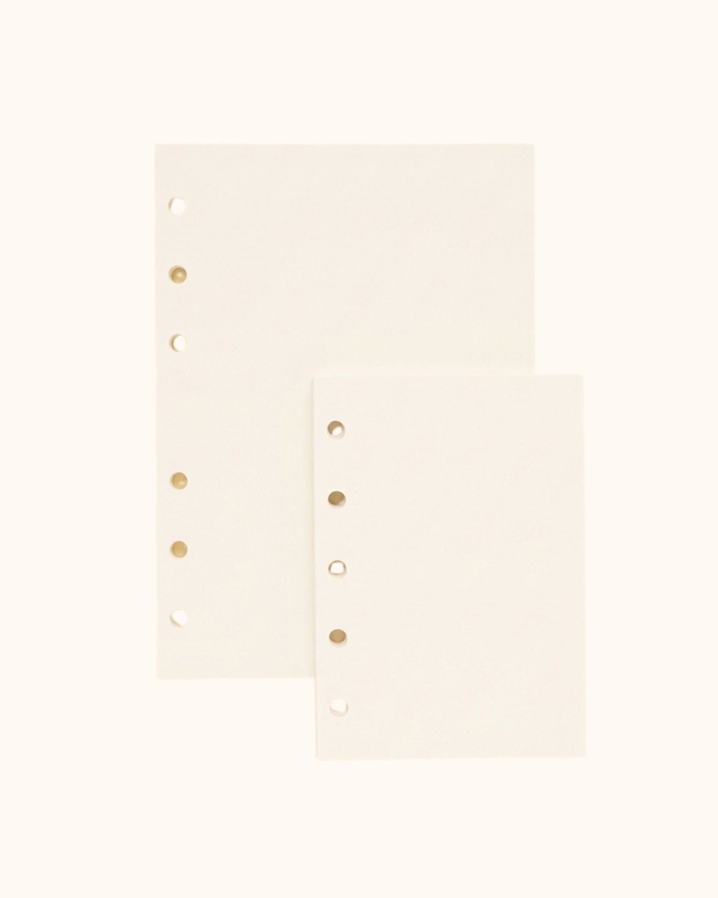 Overhead view of two Kuura premium blank journal refill sheets, showing A6 and A7 size options with standard 5-hole and 6-hole punching for ring binders. Smooth, bleed-resistant paper ideal for sketching and free-form journaling.