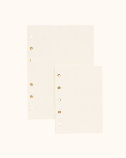Overhead view of two Kuura premium blank journal refill sheets, showing A6 and A7 size options with standard 5-hole and 6-hole punching for ring binders. Smooth, bleed-resistant paper ideal for sketching and free-form journaling.