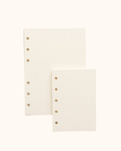 Overhead view of two Kuura premium dotted bullet journal refill sheets in A6 and A7 sizes. Features standard 5-hole and 6-hole punching and high-quality paper, perfect for aesthetic habit tracking, layout design, and organized note-taking.