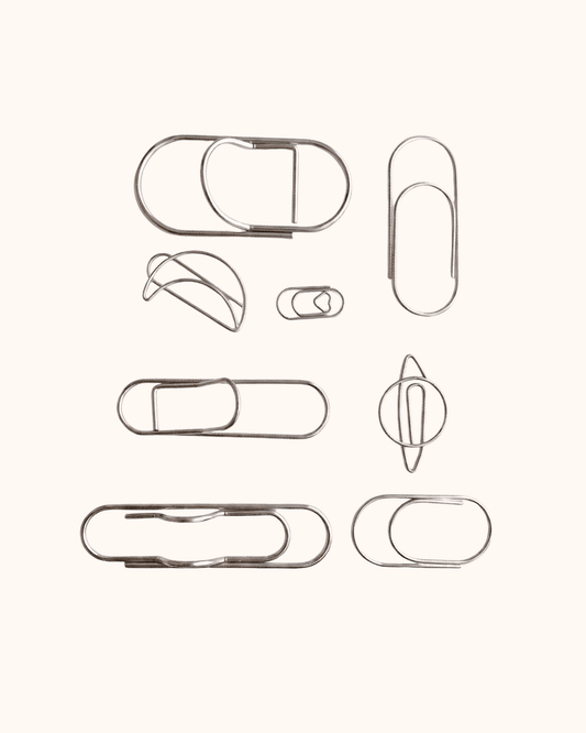 An overview of the Assorted Silver Wire Journal Clip Set, featuring 8 minimalist shapes including a delicate heart, a celestial planet, and wide pen loop designs. Perfect for marking planner pages or securing loose notes.