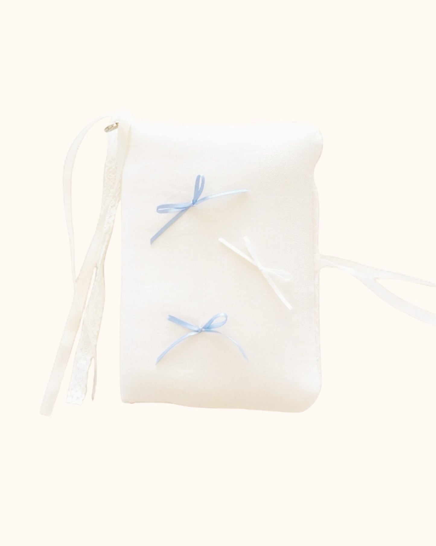 A plush kuura Balloon A5 Journal & Notebook Cover with Pockets in a gentle cream shade. Designed with a soft aesthetic feel, this journal sleeve features misty blue and white bows, secured with delicate white lace and ribbon wraps.