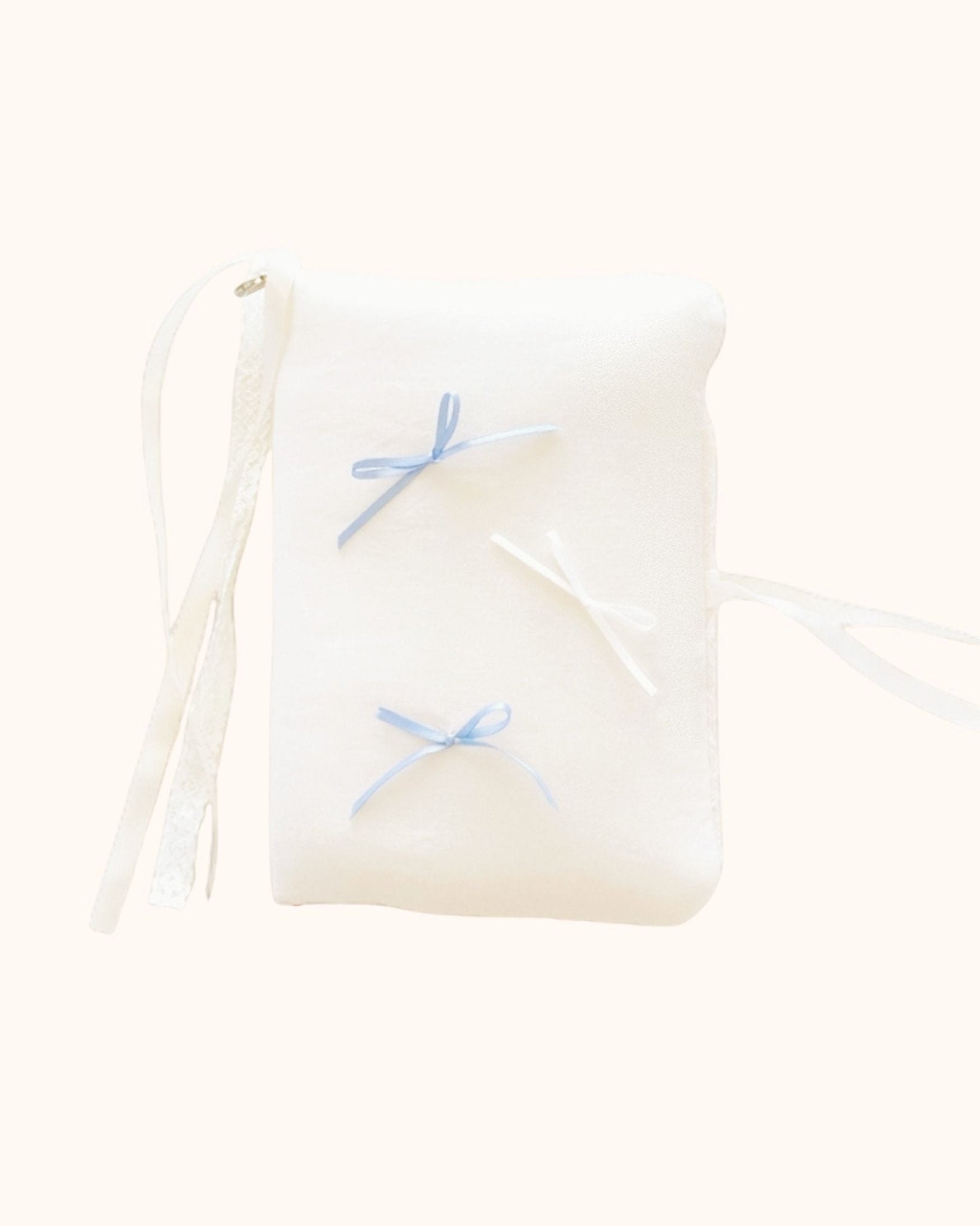 A plush kuura Balloon A5 Journal & Notebook Cover with Pockets in a gentle cream shade. Designed with a soft aesthetic feel, this journal sleeve features misty blue and white bows, secured with delicate white lace and ribbon wraps.