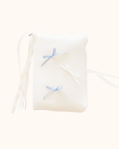 A plush kuura Balloon A5 Journal & Notebook Cover with Pockets in a gentle cream shade. Designed with a soft aesthetic feel, this journal sleeve features misty blue and white bows, secured with delicate white lace and ribbon wraps.