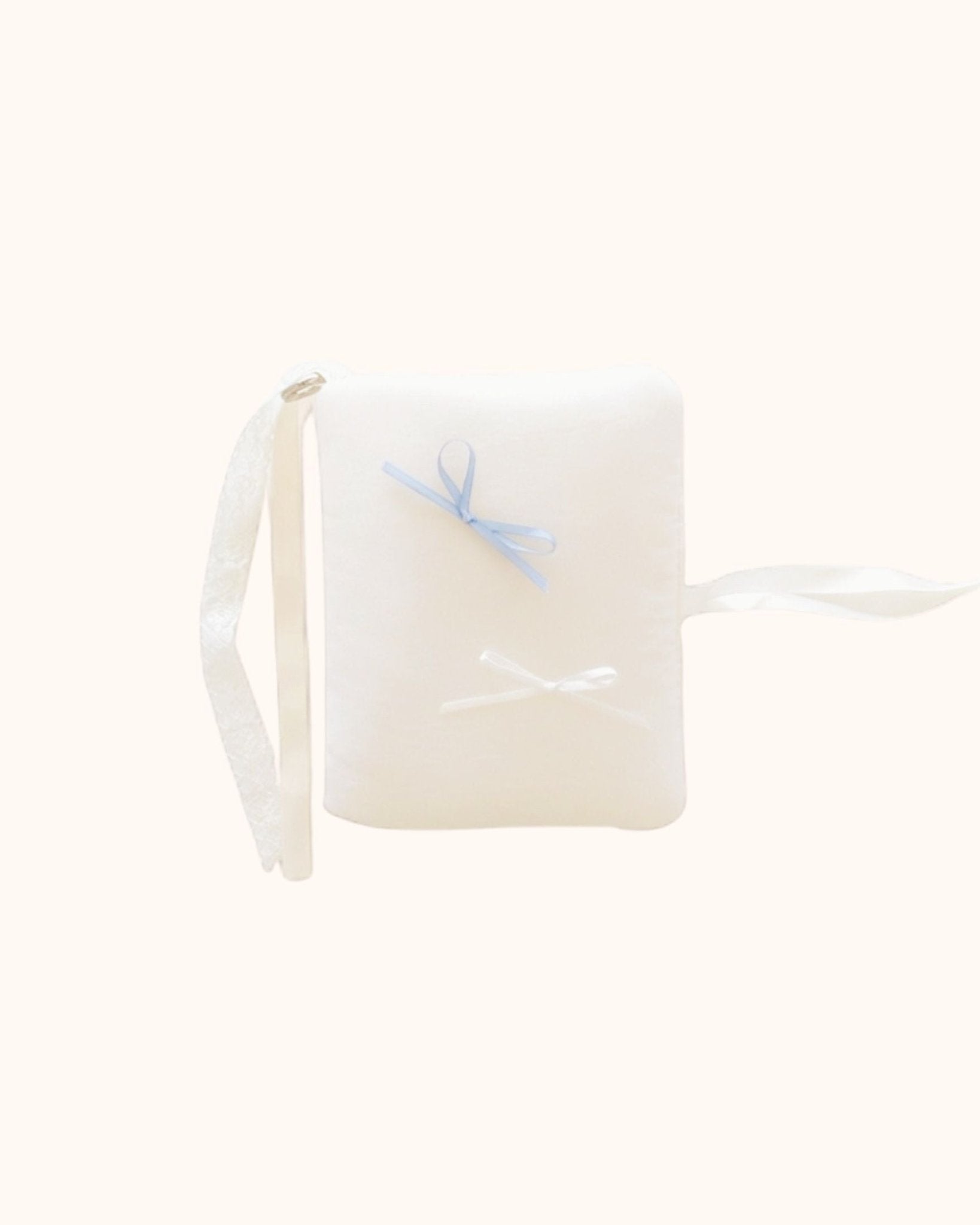 Close-up of the kuura Balloon A6 Journal & Notebook Cover with Pockets in a soft cream color. This kawaii puffy journal sleeve features a plush texture, decorated with delicate white and misty blue bows, complete with beautiful white lace and ribbon tie closures.