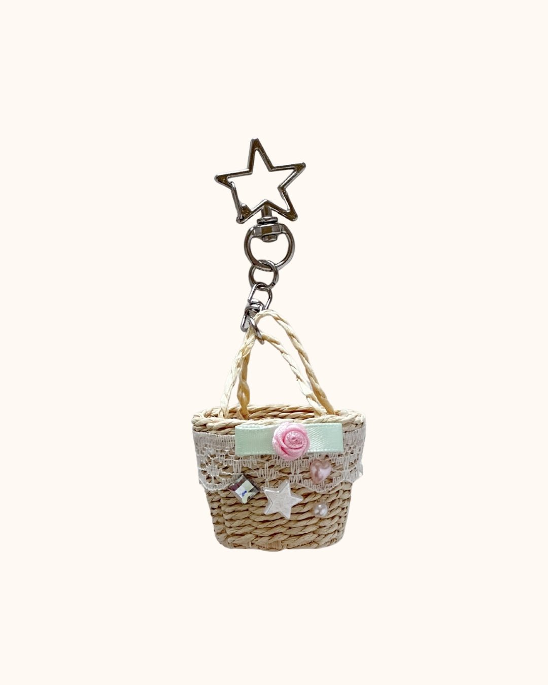 Kuura Little Meadow Charms Picnic Basket, a woven straw mini basket with lace, mint ribbon, pink rose and pearl beads on a star clasp. Cute keychain charm