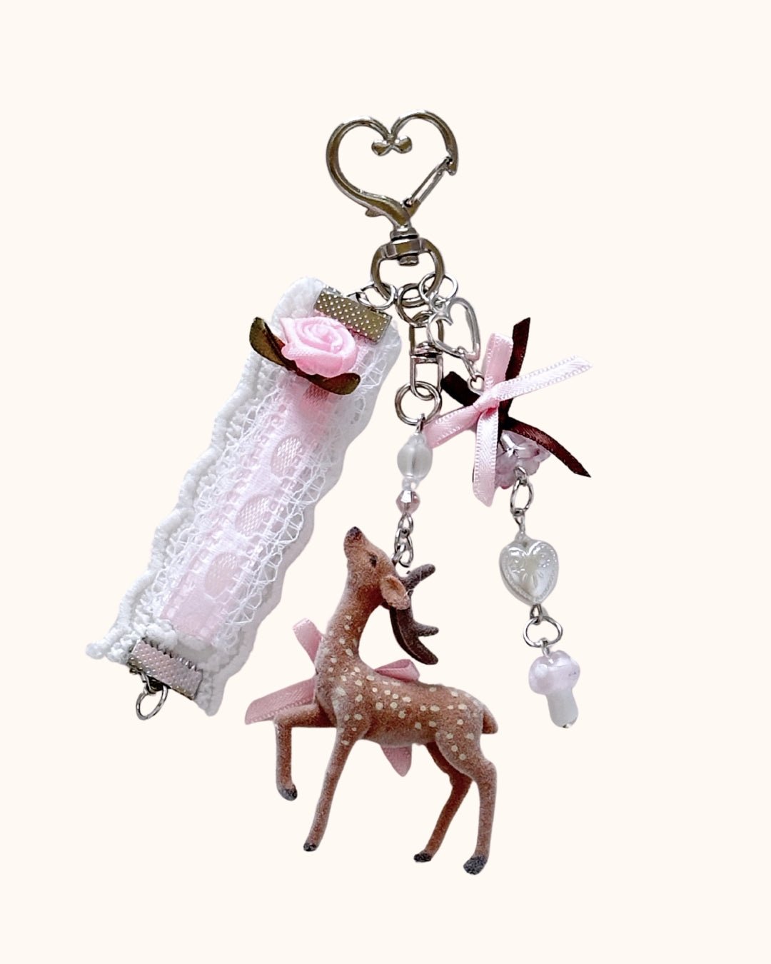 Kuura Little Meadow Charms Deer, a flocked spotted deer with pink ribbon, lace rose strap, heart bead and mushroom dangle on a heart clasp. Journal charm