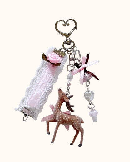 Kuura Little Meadow Charms Deer, a flocked spotted deer with pink ribbon, lace rose strap, heart bead and mushroom dangle on a heart clasp. Journal charm