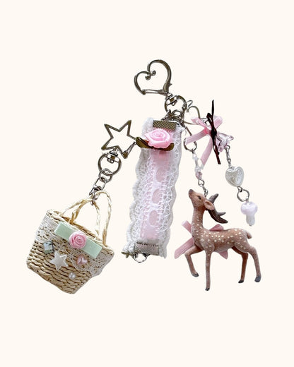 Kuura Little Meadow Charms Set of 2, a flocked deer charm and a lace-trimmed woven picnic basket charm on star and heart clasps. Cottagecore bag charm