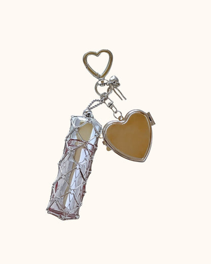 Kuura Macrame Journal Charm with Mirror in Heart, a silver metal net pouch holding a lipstick with a heart compact mirror and clasp. Lipstick holder