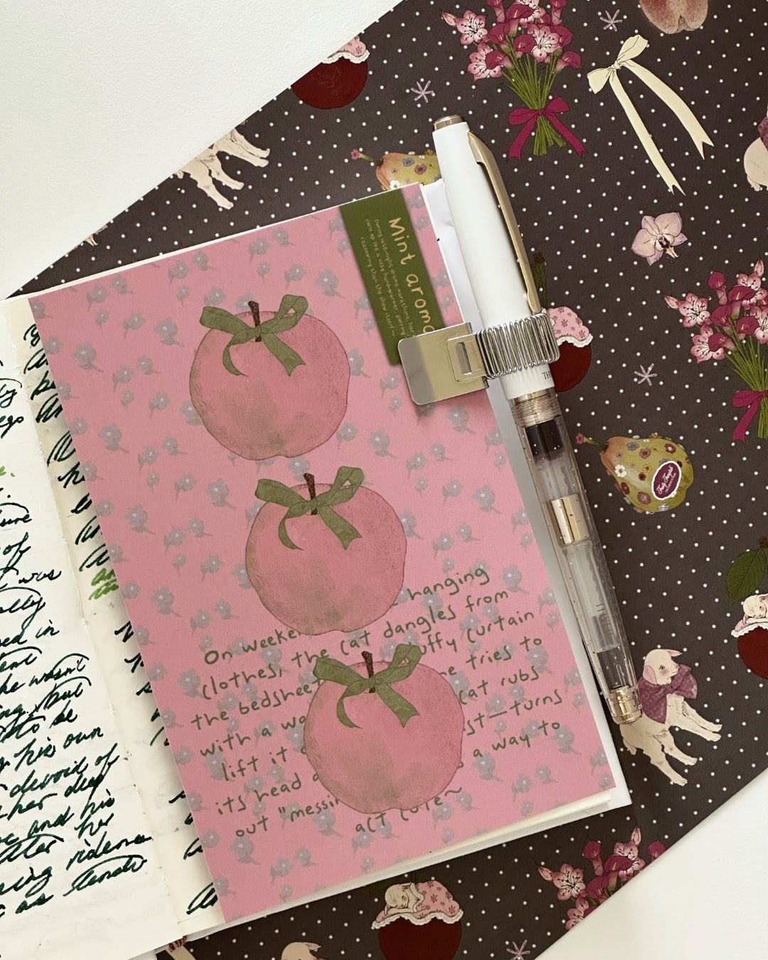 Kuura Minimalist Pen Loop in silver, a slim metal clip-on loop holding a fountain pen on an open journal page. Aesthetic journaling setup essential