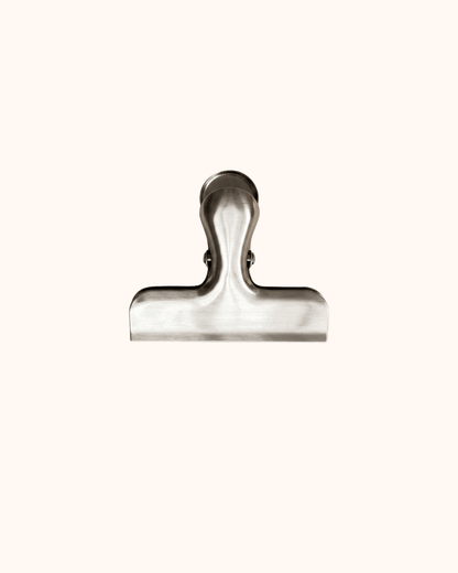 A view of the Minimalist Silver Journal & Scrapbook Clip. Featuring a brushed silver finish and a sturdy wide opening, this weighted clip is designed to keep thick notebooks and chunky bujo spreads perfectly flat.