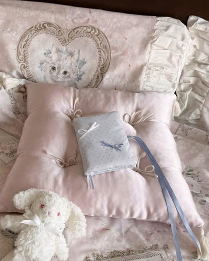 Kuura Reverie A5 & A6 Journal & Notebook Cover in Misty Blue Polka Dots, on a tufted pink silk cushion beside a plush bunny. Romantic gift for her